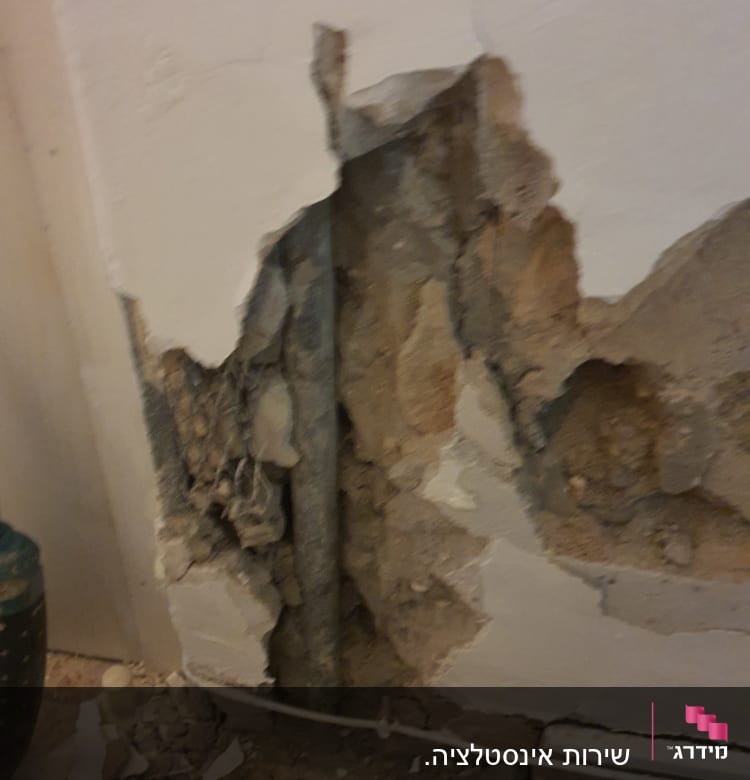 קיר שבור עם צינור חשוף ועבודות תיקון